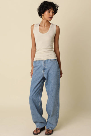 Cream ribbed sleeveless scoop-neck tank top worn with wide-leg blue jeans