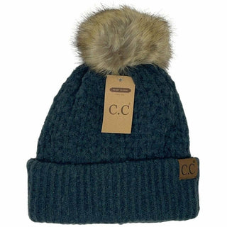 Dark teal knit beanie with smocked stitch, faux fur pom, and cuffed brim