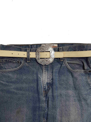 Cream suede leather belt with silver engraved western floral concho buckle on blue jeans