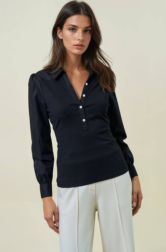 Woman wearing a black long-sleeve shirt with white buttons and white pants on a beige background