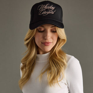 Woman wearing a black cap with 'Whiskey Cowgirl' text on a gray background