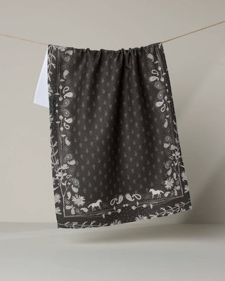 Black fabric with white floral and animal patterns hanging on a line against a beige background