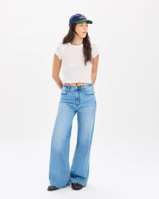 Light blue high rise wide leg jeans paired with white crop top and navy baseball cap