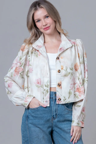 Woman wearing a floral blouse and blue jeans on a gray background