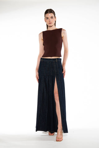 Woman wearing a brown sleeveless top and long dark denim skirt on a white background