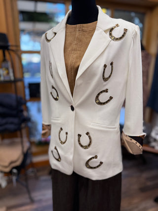 White blazer with gold horseshoe appliqués and tan suede cuffs on mannequin