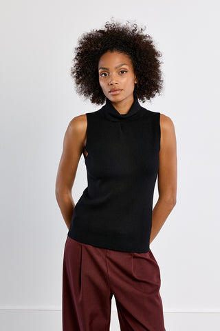 Black sleeveless turtleneck knit sweater worn with burgundy wide-leg trousers