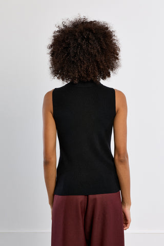 Black sleeveless ribbed knit turtleneck sweater, back view, paired with burgundy trousers