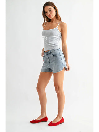 Woman wearing a gray tank top and denim shorts on a white background