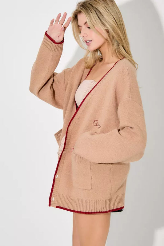 Woman wearing a beige cardigan with red trim on a white background