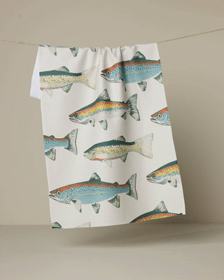 Tea towel with fish pattern hanging on a line against a beige background