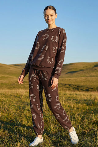 Woman wearing a brown outfit with horseshoe pattern standing in a field