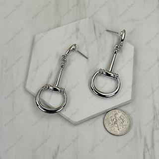 Silver horsebit drop earrings with D-ring detail, shown beside a dime for scale