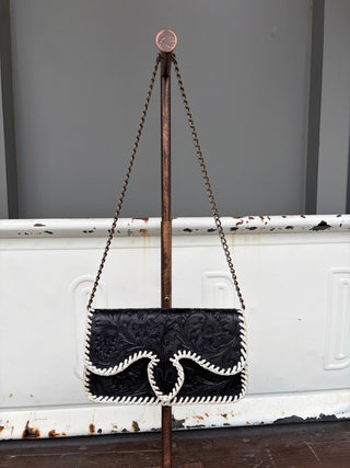 Black tooled leather clutch bag with white whipstitch trim and brass chain strap