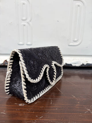 Black tooled leather clutch bag with white braided whipstitch edging and handle