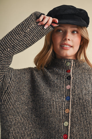 Black and taupe knit cardigan with multicolored buttons, modeled with black baker boy cap