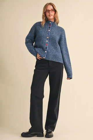 Blue marled knit cardigan with colorful buttons, worn with black wide-leg trousers