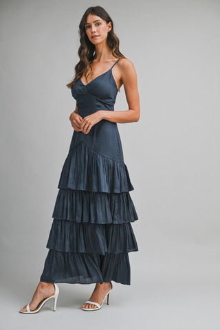 Woman wearing a dark blue tiered dress on a gray background