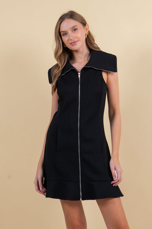 Woman wearing a black sleeveless dress with a zipper on a beige background