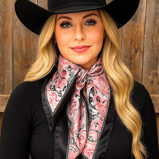 Woman wearing a black cowboy hat and pink patterned scarf against a wooden background