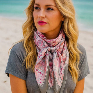 Woman wearing a pink patterned scarf on a beach