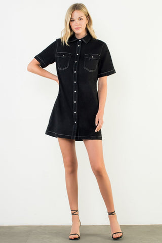 Woman wearing a black denim dress against a white background