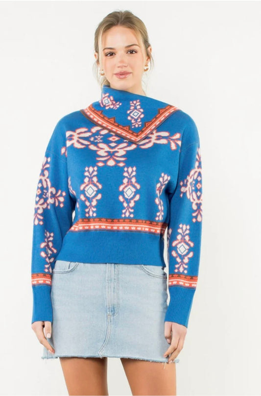 Woman wearing a blue patterned sweater and denim skirt on a white background