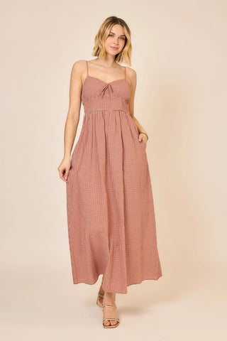 Woman wearing a pink checkered dress against a beige background