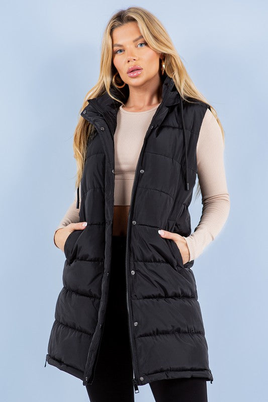 Woman wearing a black puffer vest against a light blue background