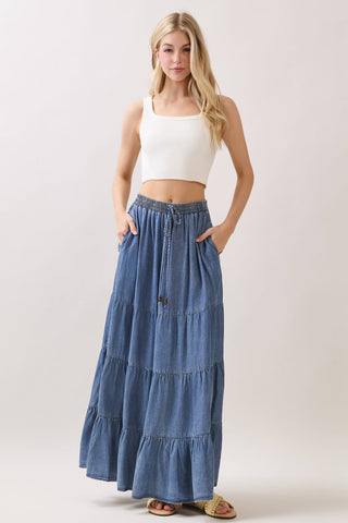 Woman wearing a white tank top and blue denim skirt on a plain background