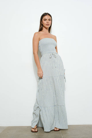 Woman wearing a light blue checkered dress against a white background