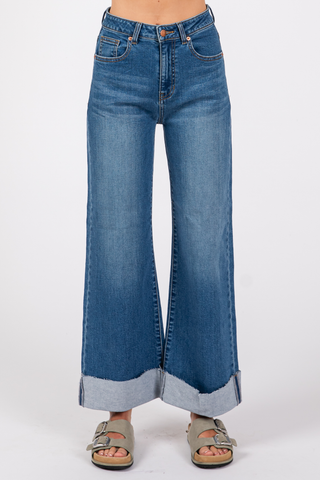 A pair of blue denim Bianca A-Line wide cuff jeans with a cuffed hem, displayed on a model without showing the upper part of the body.