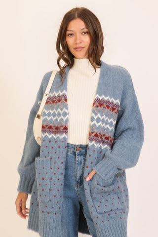 Woman wearing a long blue cardigan with a patterned design on a white background