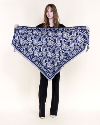 Model holding open a large navy and white paisley triangular scarf with fringe edges