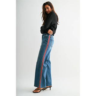 Model wearing high-rise wide leg jeans with red and white side stripe detail, side view