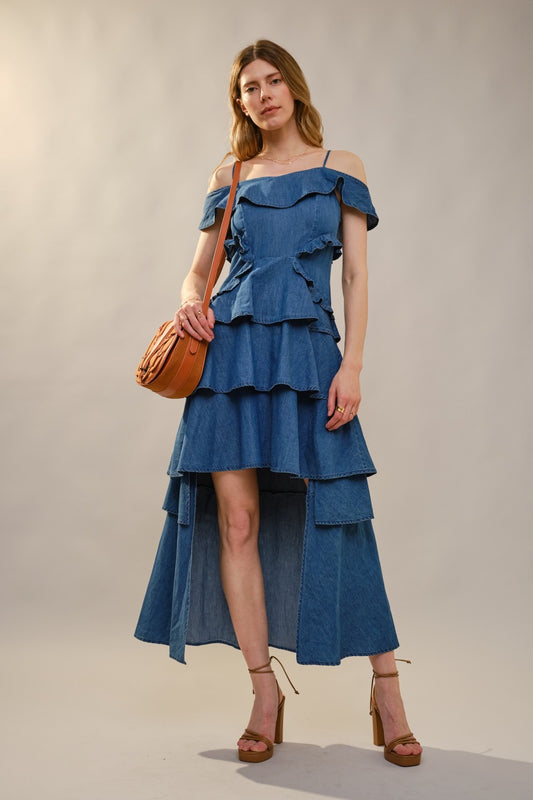 Woman wearing a blue off-shoulder dress with ruffles against a plain background