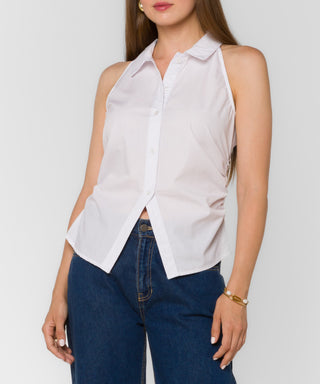 Woman wearing a white sleeveless blouse and blue jeans on a plain background