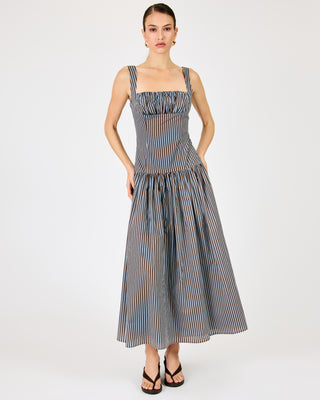 A woman modeling a sleeveless midi dress with thin shoulder straps, a gathered square neckline, and a tiered skirt. The dress has a vertical stripe pattern in navy blue and white.
