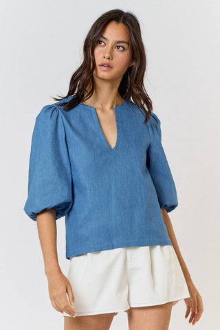 Woman wearing a blue blouse and white shorts on a plain background