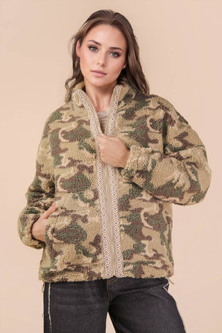 Woman wearing a camouflage jacket with a beige background