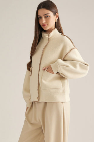 Cream oversized fleece jacket with brown scallop trim detailing and front pockets