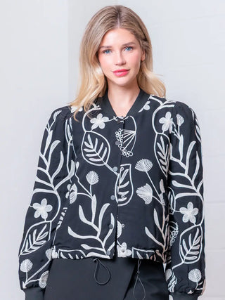 Woman wearing a black floral patterned shirt against a plain background