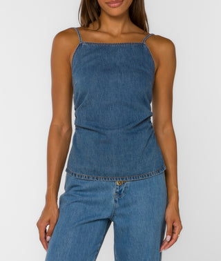 Woman wearing a blue denim top and jeans on a white background