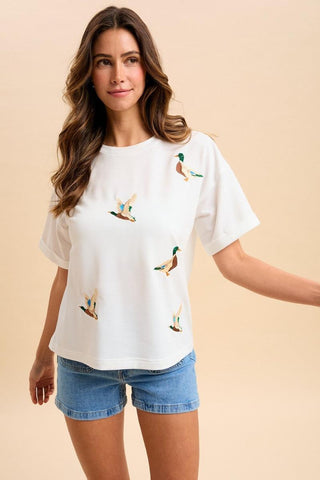 Woman wearing a white t-shirt with duck designs on a beige background