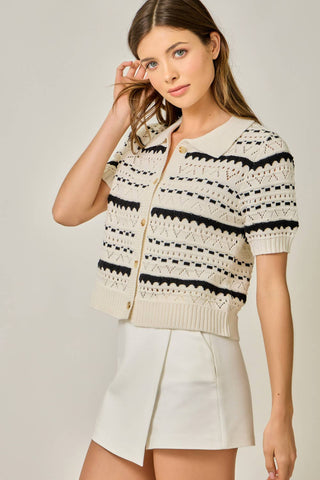 Woman wearing a cream and black patterned cardigan with a plain background