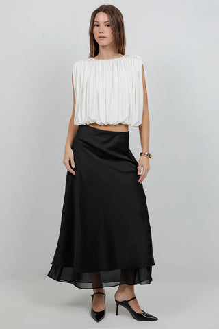 Woman wearing a white top and black skirt on a plain background
