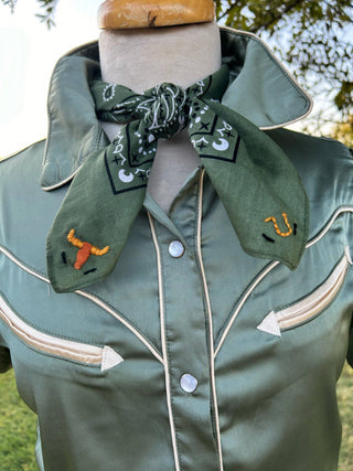 Green jacket with decorative elements on a mannequin against a natural background