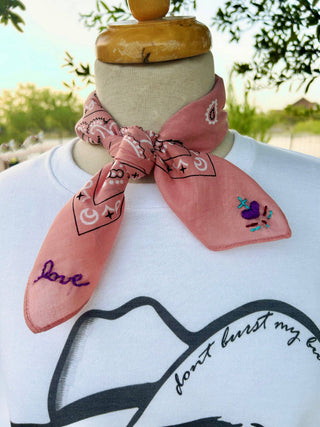 Mannequin wearing a white shirt with black text and a pink bandana with designs and text.