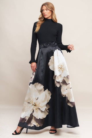 Woman wearing a black dress with large white floral patterns on a plain background