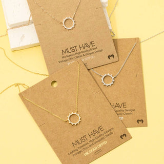 Two necklaces on brown cards with 'Must Have' branding on a yellow background